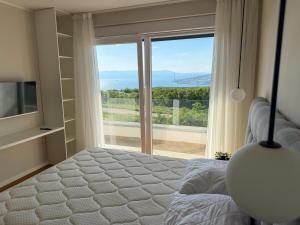 a bedroom with a bed and a large window at VILLA MARIS SMRIKA -heated pool in Šmrika