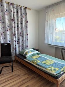 a bedroom with a bed and a chair and a window at Sylbacher Gästehaus in Bad Salzuflen