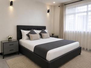 a bedroom with a large bed and a window at Naka Executive Suites With Balcony, Amazing View of Lake Nakuru, GYM in Nakuru