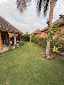 a yard with a palm tree and a house at Residence Mangrove Saly in Ngaparou