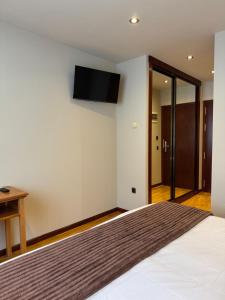 a bedroom with a bed with a television on the wall at Hotel Montaña Central in Caborana