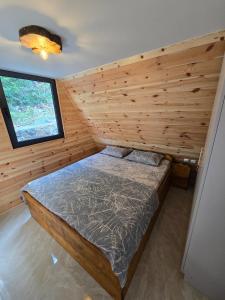 a bed in a room with a wooden wall at The Quiet Wild in Briska Gora