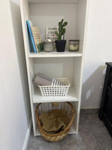 a white book shelf with a basket and a plant at La Seven Dpto Turístico in Colón