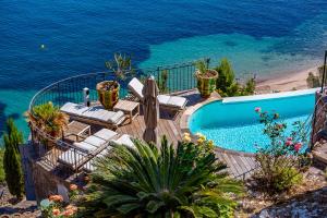 a swimming pool with chairs and the ocean at La Coraillère Waterfront Villa with Private Pool and Sea Access in Théoule-sur-Mer