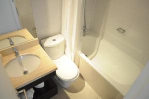 a bathroom with a toilet and a sink and a tub at Kennedy Apartments Los Militares in Santiago