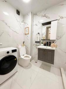 a white bathroom with a toilet and a sink at My Sweet Apartment in Tbilisi City +26 photos