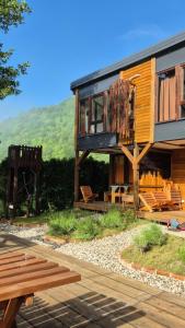 a wooden house with a bunch of chairs and a bench at Roots&River in Jezero