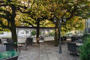 a patio with tables and chairs under trees at Boutique Hotel Waldegg in Lucerne
