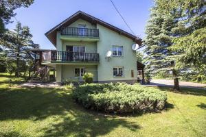 a large house with a balcony on top of a yard at Chatka Mysliwego Wladka in Wola Piotrowa