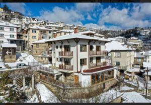 a building in a city with snow on the ground at Rhodope House Momchil Yunak in Momchilovtsi