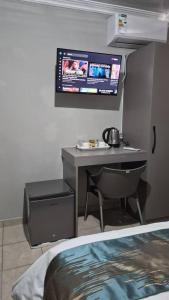 a room with a desk and a tv on the wall at La Palma Suites Guest House in Mochudi