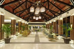 a lobby with tables and chairs and a ceiling with chandeliers at Mercure Manado Tateli Resort and Convention in Manado