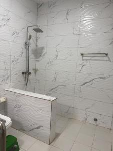 a bathroom with a shower with white marble walls at Villa S in Ouagadougou