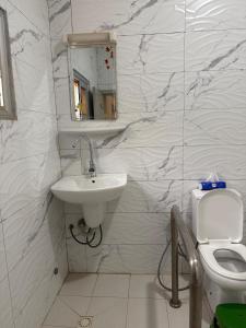 a white bathroom with a sink and a toilet at Villa S in Ouagadougou +2 photos