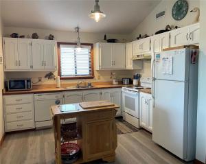 a kitchen with white cabinets and a white refrigerator at Hurricane Charlie's in Duck