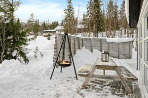 a snow covered yard with a table and a fire pit at Flott hytte på Bjørgan in Grong