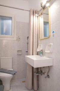 a bathroom with a sink and a toilet and a mirror at To Steno in Kamares
