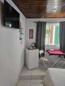 a bedroom with a bed and a table and a window at Pousada Bem Te Vi Lumiar in Lumiar