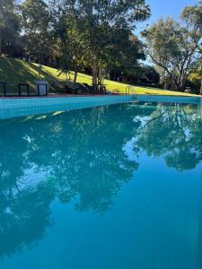 a pool of blue water with trees in the background at Hospedaria do Feno in Brotas