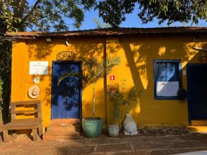 a yellow house with a cat sitting in front of it at Hospedaria do Feno in Brotas