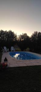 a swimming pool with two white chairs next to it at La Elvira in San Pedro