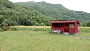 a red shed with a bench in a field at Balta Roșie in Râu de Mori +6 photos