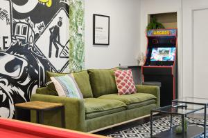 a living room with a green couch and a video game at MtlVacationRentals - The Entertainer in Montreal