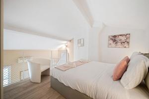 a white bedroom with a bed and a white chair at VILLA CARLA appartement central zone piétonne clim in Menton +8 photos