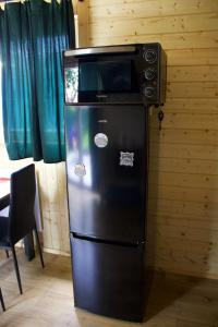 a refrigerator with a microwave on top of it at By The Lake - Domki I Sauna Nad Jeziorem in Załęże