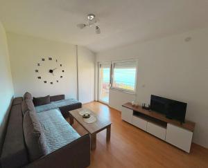 a living room with a couch and a clock on the wall at Indijano Apartment in Ohrid