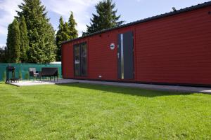 a red building with a table and chairs in a yard at By The Lake - Domki I Sauna Nad Jeziorem in Załęże