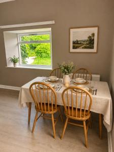 a dining room table with four chairs and a window at Ivy golf cottage in Leven +15 photos