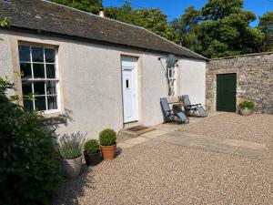 a cottage with two chairs sitting outside of it at Ivy golf cottage in Leven