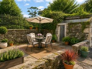 a table and chairs with an umbrella in a garden at Ivy golf cottage in Leven
