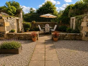 a patio with an umbrella and a table and chairs at Ivy golf cottage in Leven