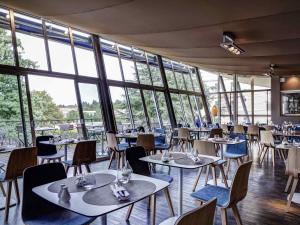 a restaurant with tables and chairs and windows at Mercure Lyon Charbonnières in Charbonnières-les-Bains