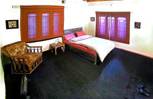 a bedroom with a bed and a chair at Cottage De Hunza- A Soul Retreat Sanctuary in Hunza Valley