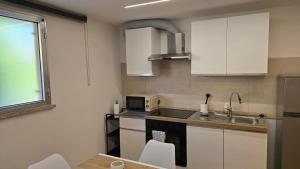 a small kitchen with white cabinets and a microwave at Tiny House in Quarto dʼAltino
