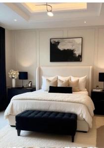 a bedroom with a large white bed with a black ottoman at Résidence le HAvre in Laval