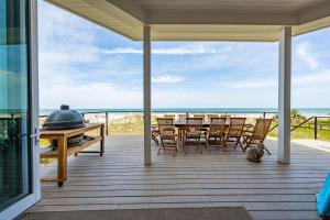 a porch with a table and chairs on the beach at Seaview Serenity - Team Joseph Ellen in Jacksonville Beach