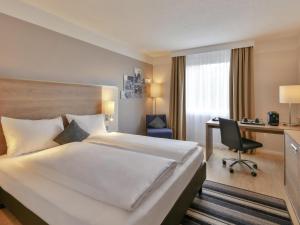 a hotel room with a large bed and a desk at Mercure Aachen Europaplatz in Aachen +71 photos