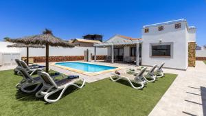 a villa with a swimming pool with lawn chairs and an umbrella at Villa with private pool, near beach and golf Caleta de Fuste- Villa Charlotte in Costa de Antigua