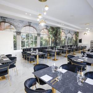 a dining room with tables and chairs and windows at Hotel Doc in Vairano Scalo