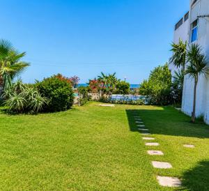 a garden with grass and stepping stones in front of a building at Beachside Garden Apartment in Marina Smir in Marina Smir