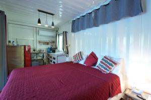 a bedroom with a bed with red sheets and a kitchen at Libertas in Pointe d'Esny