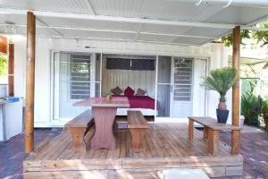a patio with a table and benches on a deck at Libertas in Pointe d'Esny +1 photo