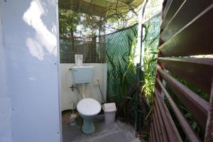 a small bathroom with a toilet in a fence at Libertas in Pointe d'Esny