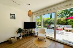 a living room with a chair and a television at Spacious cocoon with pool in La Rochelle in La Rochelle
