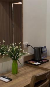 a green vase with flowers on a wooden table at Hotel Santal in Bukhara