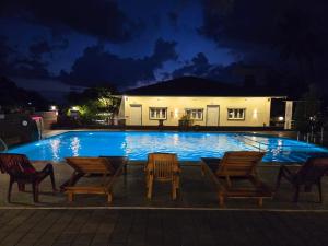 a swimming pool at night with chairs and a house at Mai's Beach Resort in Malvan